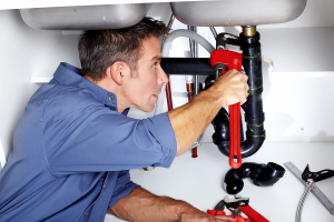 A plumber fixing a drain that is clogged