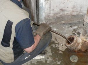 A plumber snaking a drain to unclog it
